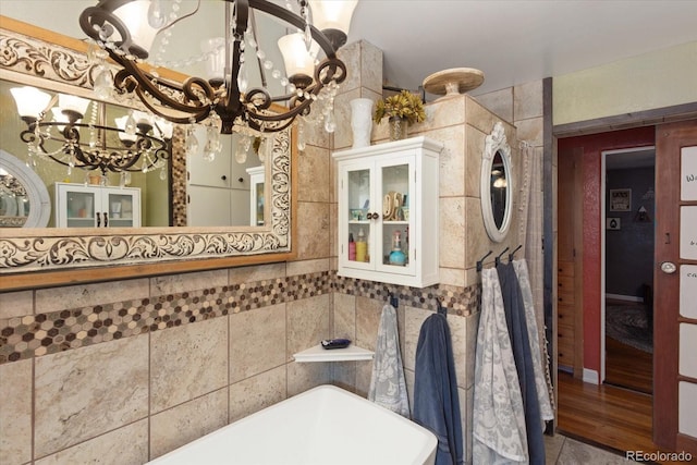 bathroom with a washtub, tile walls, and an inviting chandelier