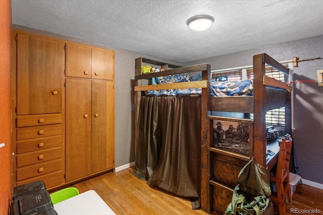 bedroom featuring a textured ceiling and light hardwood / wood-style flooring