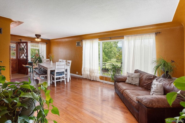 living room featuring a wealth of natural light, ceiling fan, and light wood-type flooring