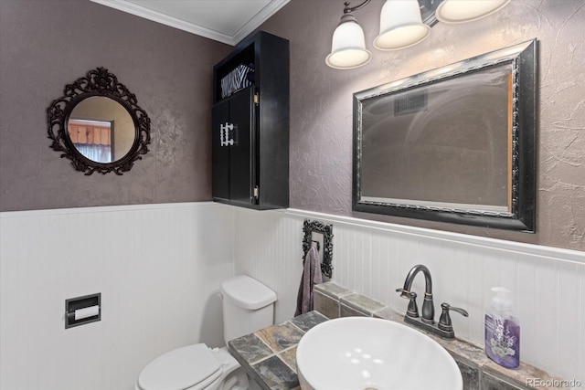 bathroom featuring toilet, sink, and ornamental molding