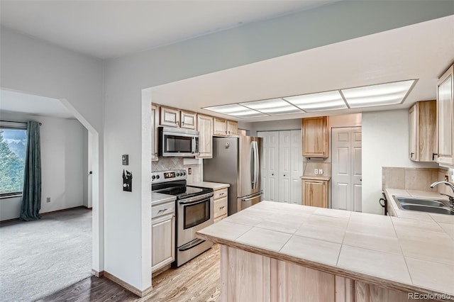 30839 Manitoba Dr, Evergreen, CO 80439 - kitchen with appliances with stainless steel finishes, tile countertops, backsplash, a peninsula, and light wood finished floors