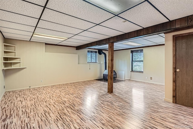 30839 Manitoba Dr, Evergreen, CO 80439 - basement featuring a wood stove, wood finished floors, a paneled ceiling, and healthy amount of natural light