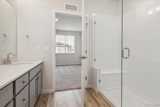 bathroom with a shower with shower door, wood-type flooring, and vanity