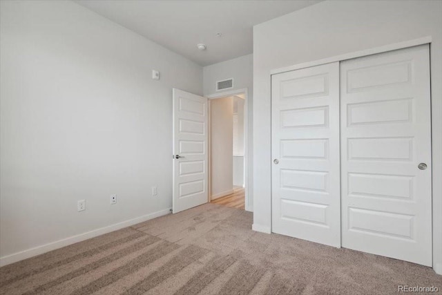 unfurnished bedroom featuring a closet and light colored carpet