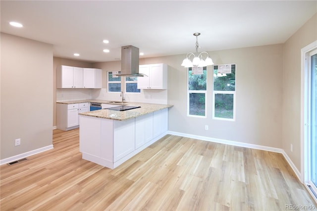 8713 E Roundtree Ave, Greenwood Village, CO 80111 - kitchen featuring island exhaust hood, a peninsula, light wood-type flooring, white cabinets, and healthy amount of natural light