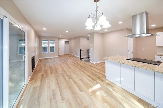 8713 E Roundtree Ave, Greenwood Village, CO 80111 - kitchen with island range hood, black electric cooktop, white cabinets, a chandelier, and light stone countertops