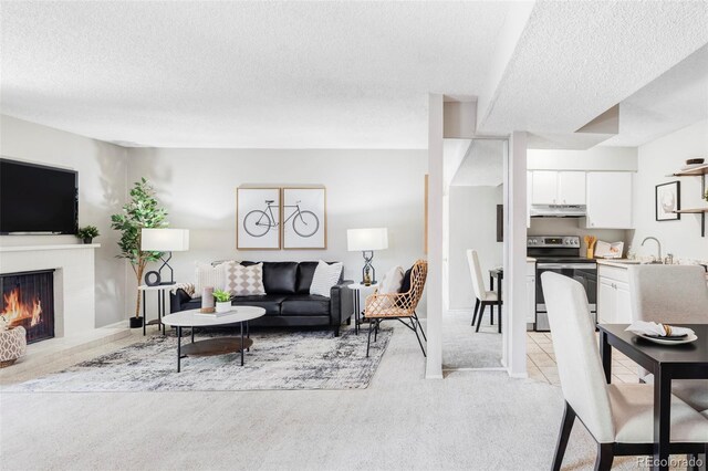 living area featuring a textured ceiling, light carpet, and a fireplace