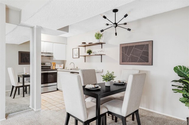 dining area with light carpet, a textured ceiling, baseboards, and a chandelier