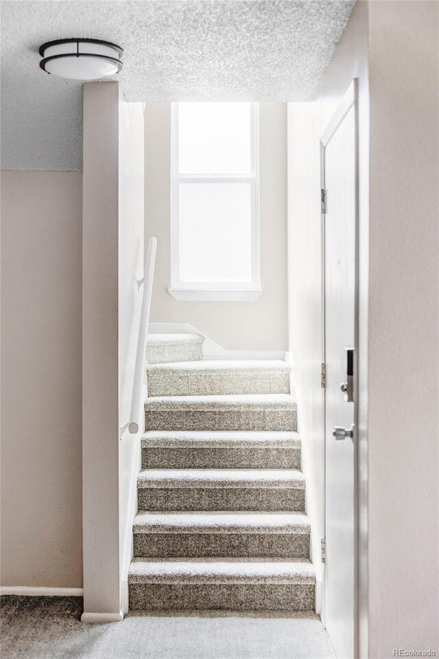 stairs with a textured ceiling and carpet