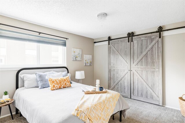 bedroom with carpet flooring, a barn door, and a textured ceiling
