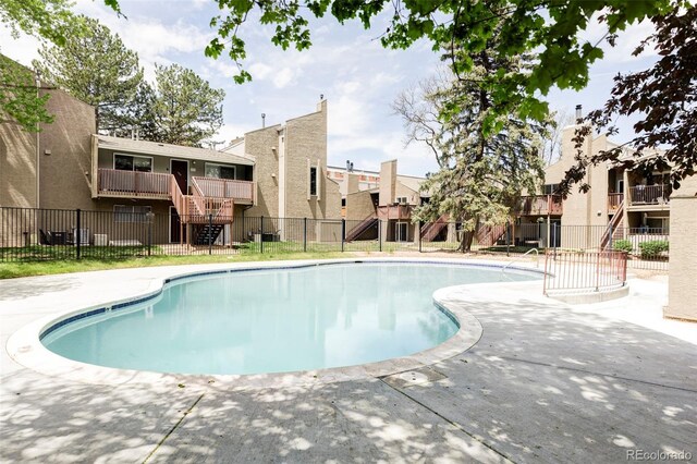 community pool with stairway, fence, a patio, and a residential view