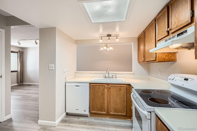 kitchen featuring white appliances, decorative light fixtures, light hardwood / wood-style floors, and sink