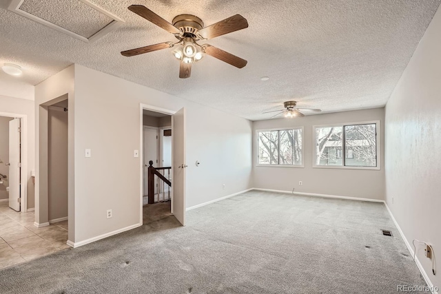 unfurnished room featuring ceiling fan, light carpet, and a textured ceiling