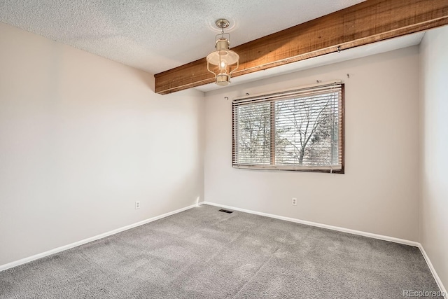 spare room featuring carpet floors, a textured ceiling, and beam ceiling