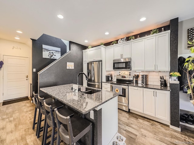 kitchen with white cabinets, stainless steel appliances, and light hardwood / wood-style flooring