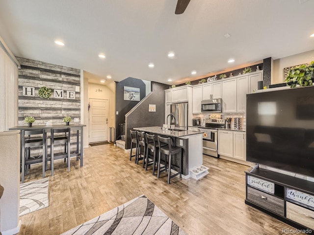 kitchen featuring a kitchen breakfast bar, light wood-type flooring, a kitchen island with sink, and stainless steel appliances