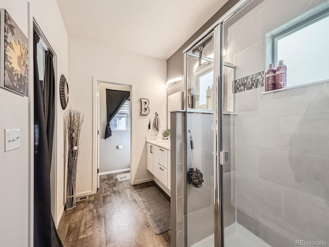 bathroom with vanity, hardwood / wood-style floors, a shower with door, and a healthy amount of sunlight