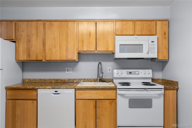 kitchen featuring white appliances, dark countertops, and a sink