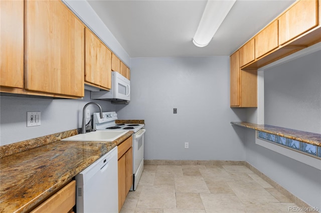 kitchen featuring a sink, baseboards, white appliances, and dark stone countertops