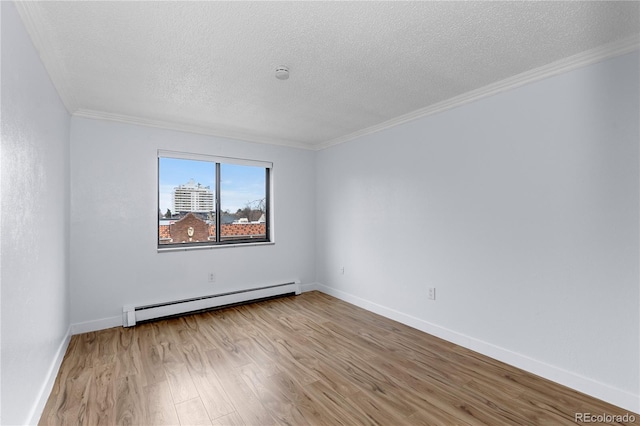 spare room with ornamental molding, a textured ceiling, wood finished floors, baseboards, and baseboard heating