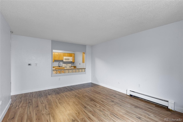 unfurnished living room with a baseboard heating unit, wood finished floors, baseboards, and a sink