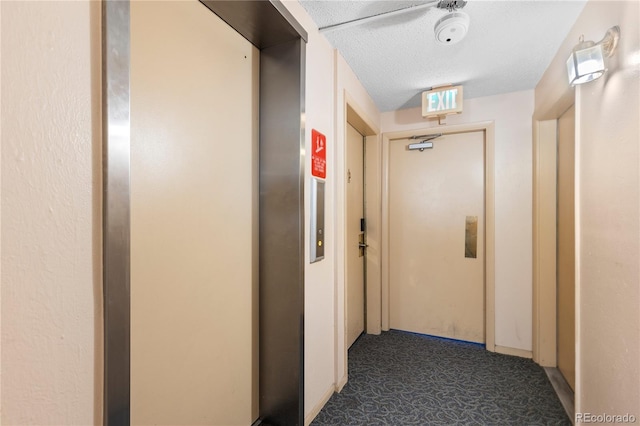 hall with elevator, carpet floors, and a textured ceiling