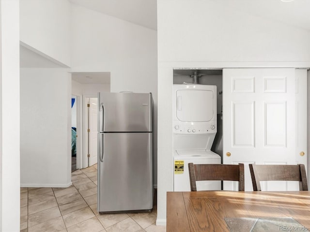 1748 Eagle St Unit B, Aurora, CO 80011 - kitchen featuring vaulted ceiling, freestanding refrigerator, stacked washing maching and dryer, and baseboards