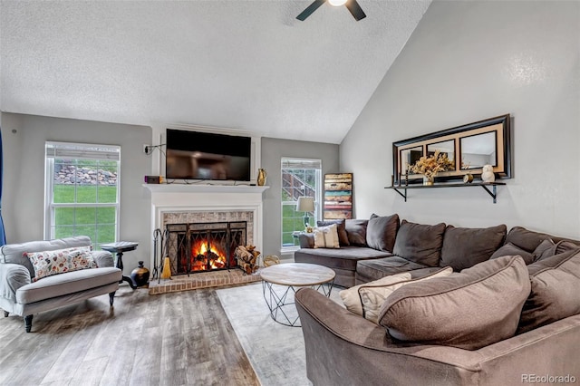 573 Entrada Dr, Golden, CO 80401 - living room featuring wood finished floors, a ceiling fan, a textured ceiling, a fireplace, and vaulted ceiling