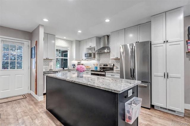 573 Entrada Dr, Golden, CO 80401 - kitchen featuring wall chimney range hood, stainless steel appliances, light wood-style floors, a center island, and recessed lighting