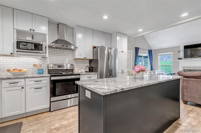 573 Entrada Dr, Golden, CO 80401 - kitchen featuring appliances with stainless steel finishes, wall chimney range hood, open floor plan, lofted ceiling, and light wood-style flooring