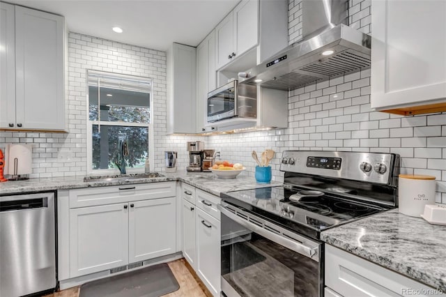 573 Entrada Dr, Golden, CO 80401 - kitchen featuring stainless steel appliances, wall chimney range hood, a sink, white cabinetry, and backsplash