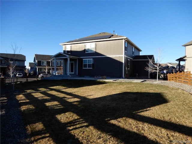 rear view of property with a lawn and solar panels