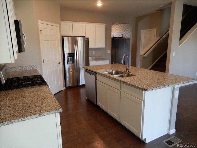 kitchen with white cabinets, appliances with stainless steel finishes, a center island with sink, and sink