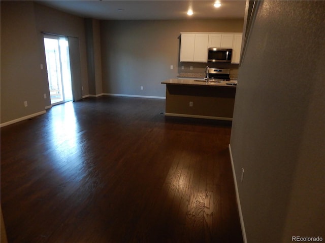 kitchen with sink, white cabinetry, stainless steel appliances, and dark wood-type flooring