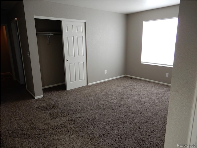 unfurnished bedroom featuring dark colored carpet and a closet