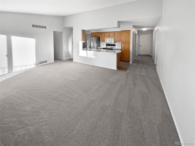 unfurnished living room with lofted ceiling, light carpet, and a textured ceiling