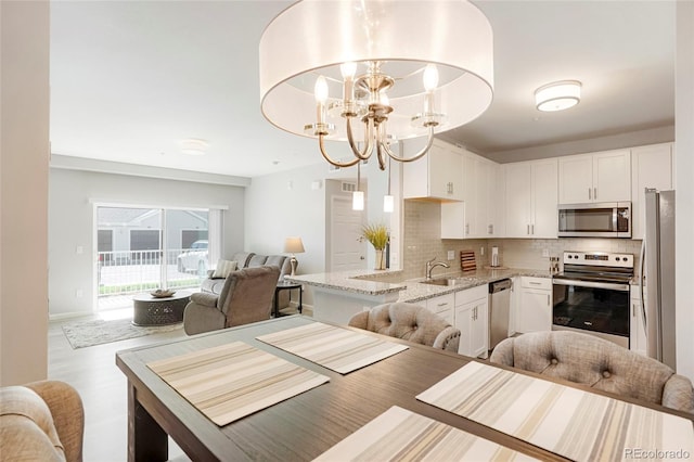 15700 E Jamison Dr Unit 8-103, Englewood, CO 80112 - kitchen featuring appliances with stainless steel finishes, open floor plan, tasteful backsplash, light stone counters, and white cabinetry
