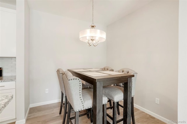 dining area with light wood-type flooring and a notable chandelier