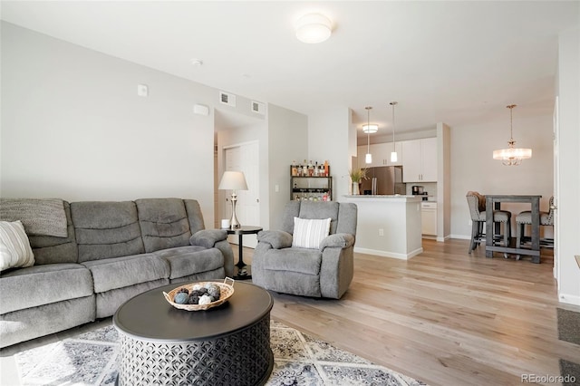 living room with light hardwood / wood-style flooring and an inviting chandelier