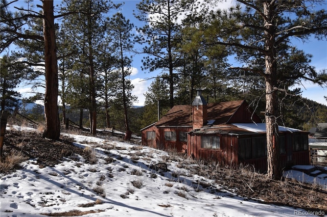 snow covered property with a chimney