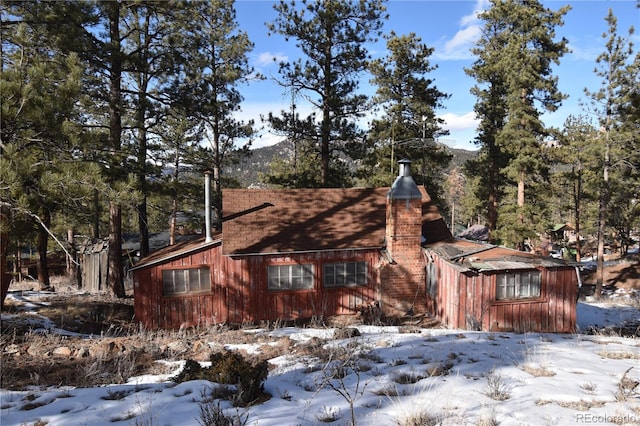 view of snow covered exterior with a chimney