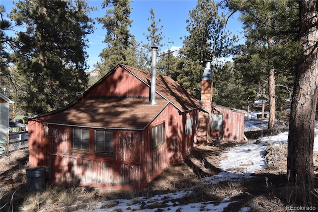 view of property exterior with a chimney and roof with shingles