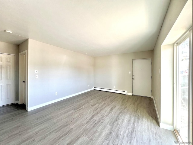 empty room with a baseboard radiator and light hardwood / wood-style flooring