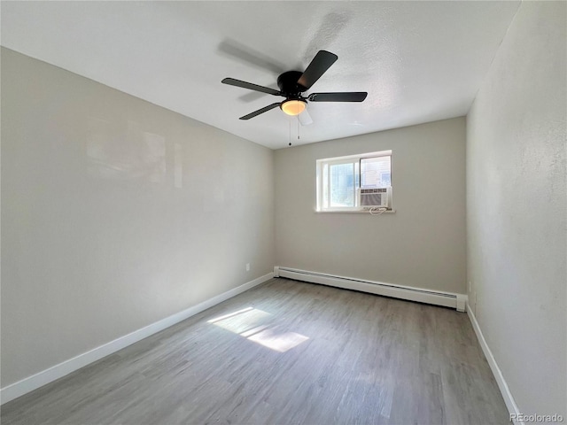 unfurnished room with ceiling fan, a baseboard heating unit, cooling unit, and light wood-type flooring