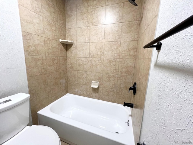 bathroom with tiled shower / bath combo and toilet