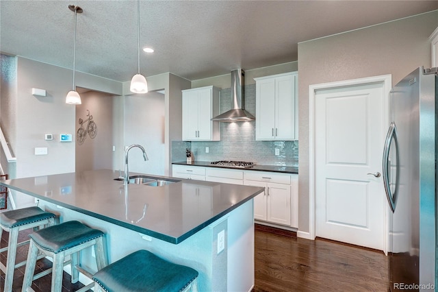 15619 Syracuse Way, Thornton, CO 80602 - kitchen with appliances with stainless steel finishes, wall chimney range hood, dark countertops, dark wood-style flooring, and a kitchen bar