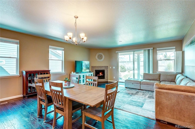 15619 Syracuse Way, Thornton, CO 80602 - dining room with wood finished floors, a chandelier, plenty of natural light, a warm lit fireplace, and a textured ceiling