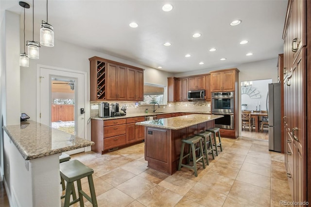 kitchen featuring appliances with stainless steel finishes, brown cabinetry, a kitchen island, and a kitchen bar