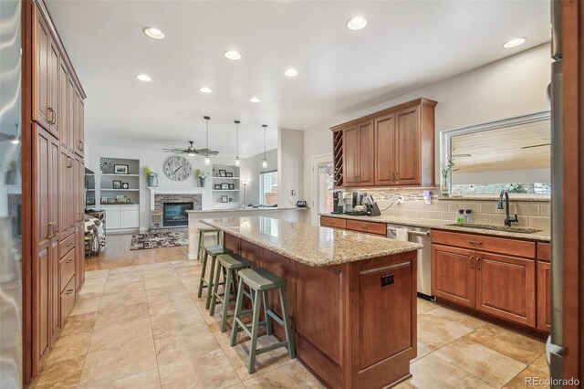 kitchen featuring a sink, open floor plan, stainless steel dishwasher, a center island, and decorative light fixtures