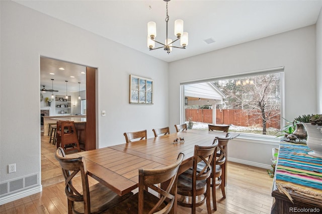 dining space featuring a chandelier, visible vents, a fireplace, and light wood finished floors